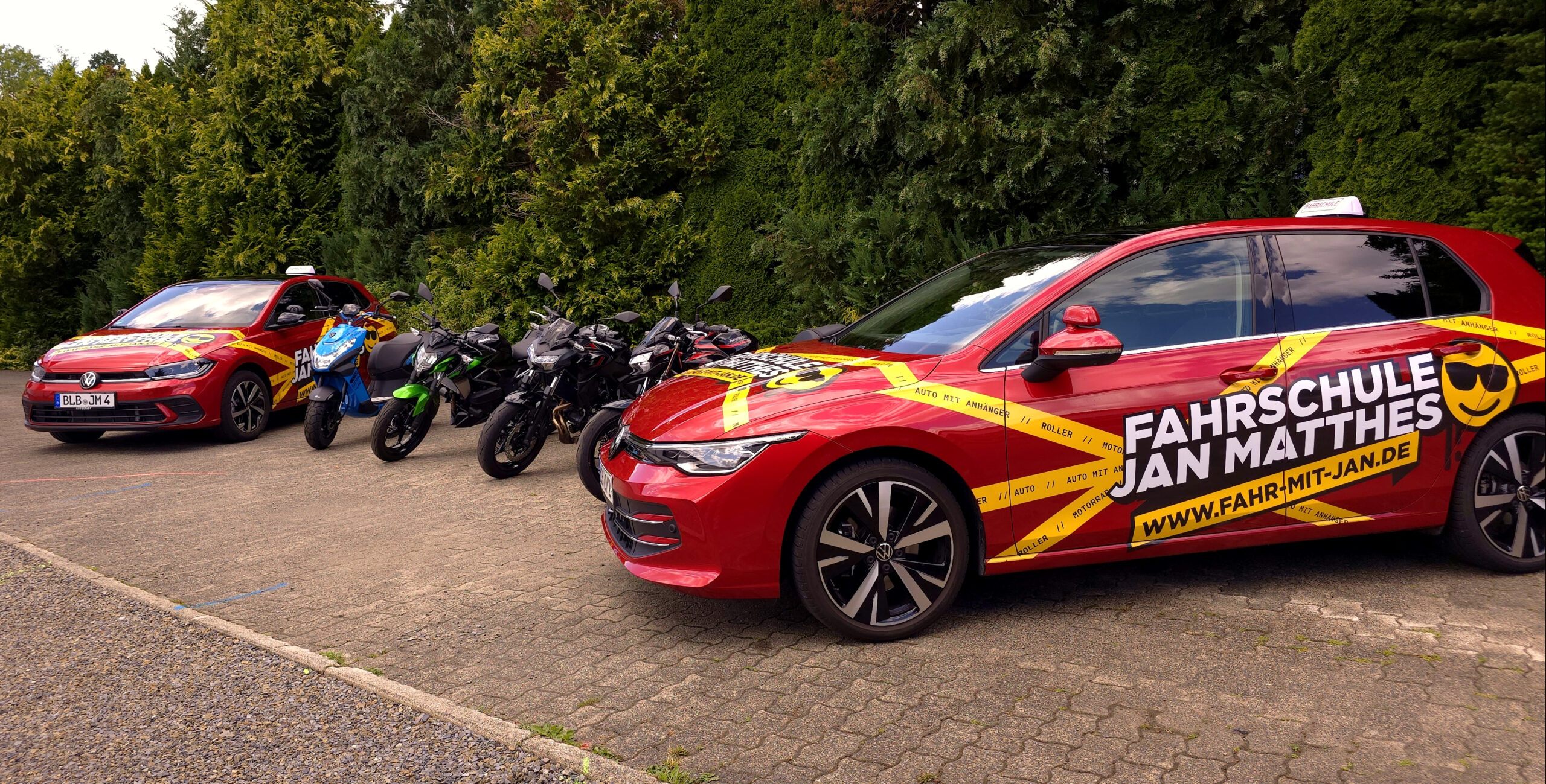 Der gesamte Fuhrpark der Fahrschule Jan Matthes in Bad Berleburg mit Autos, Motorrädern und einem Roller aufgereiht auf einem Parkplatz
