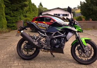 Kawasaki Z125 Motorrad der Fahrschule Jan Matthes in Bad Berleburg für die Führerscheinklasse A1 vor dem Fahrschulgebäude