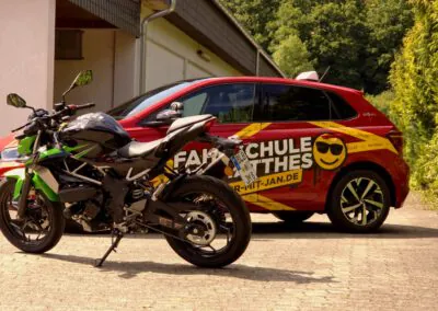 Kawasaki Z125 Motorrad für Klasse A1 vor einem roten VW Polo Fahrschulauto der Fahrschule Jan Matthes in Bad Berleburg