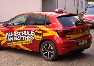 Seiten- und Heckansicht des roten VW Polo Fahrschulautos der Fahrschule Jan Matthes in Bad Berleburg mit auffälliger Beschriftung